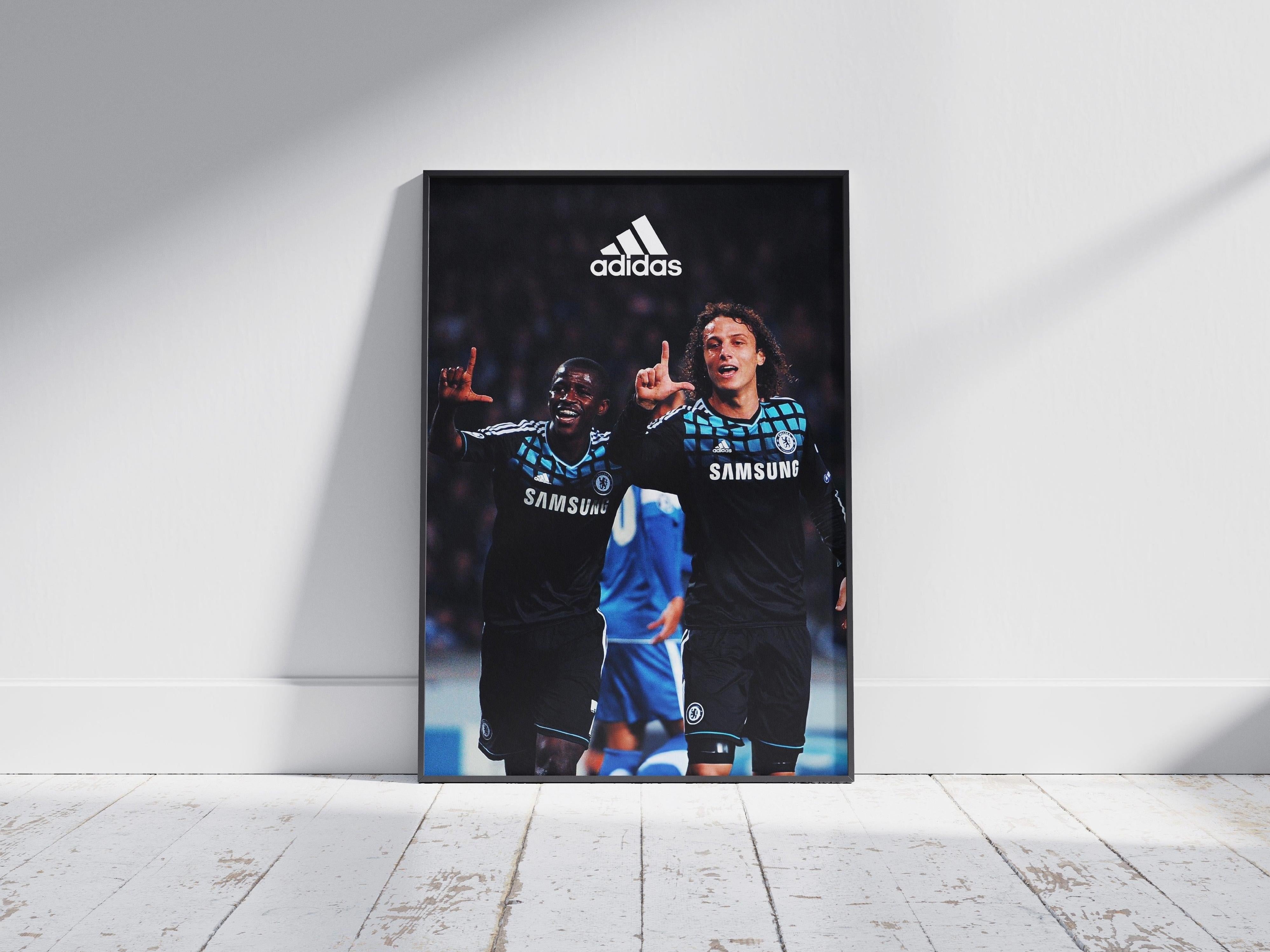 The Retro1999 Ramires x David Luiz Poster features two Chelsea stars celebrating with L gestures, Adidas logo above, and UEFA Champions League vibes—perfect football nostalgia framed on a white wooden floor.