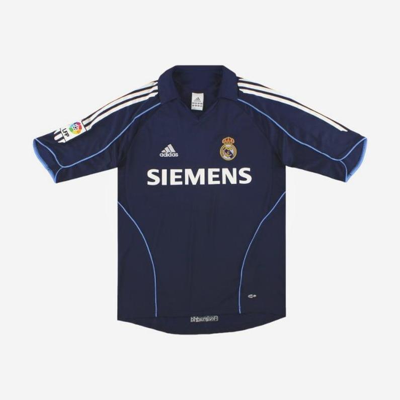 The Real Madrid 2005-06 Away Shirt by Retro1999 features navy blue with white and light blue details, Adidas logo, Siemens sponsor, club crest on chest, and La Liga patch—an authentic retro design ideal for collectors.