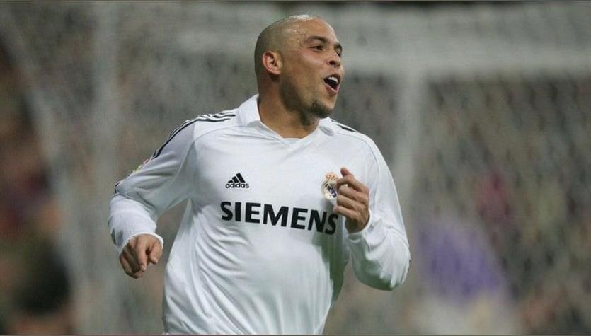 A soccer player wears the Retro1999 Real Madrid 2005-06 Home Shirt with SIEMENS on the front, running on the field and celebrating during a match in this classic retro kit.