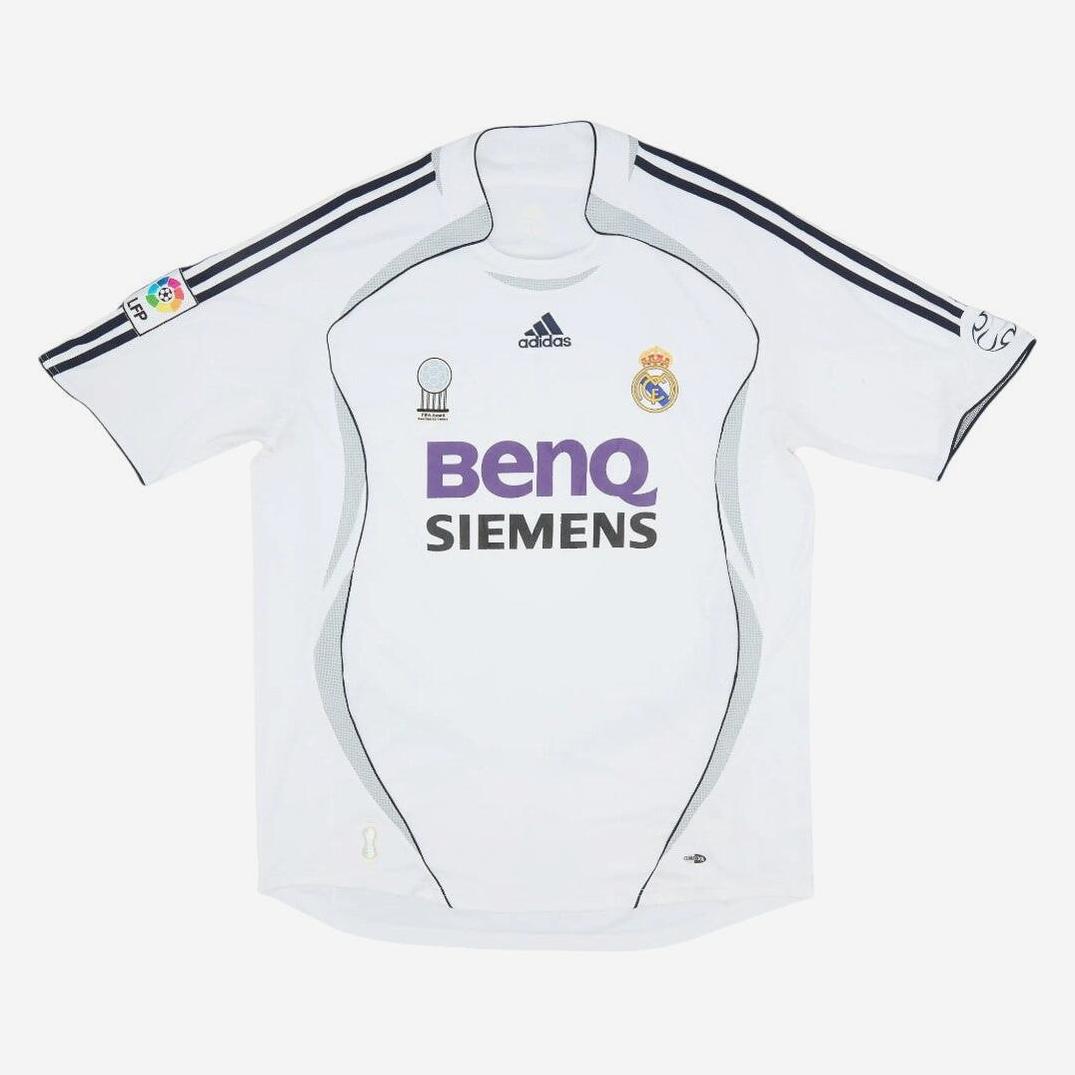 The Real Madrid 2006-07 Home Shirt by Retro1999 features a white design with grey accents, Adidas branding, La Liga patch, BenQ Siemens sponsor, and the club crest on the left chest—a classic retro kit for fans.