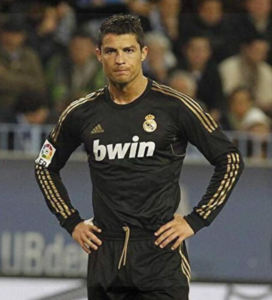 A soccer player stands with hands on hips wearing the Retro1999 Real Madrid 2011-12 Away Shirt with bwin sponsor, looking serious in this classic kit from their La Liga title-winning season.