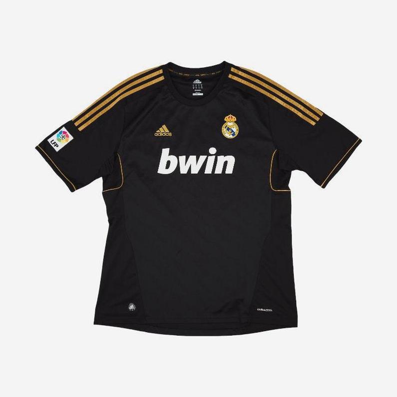 The Retro1999 Real Madrid 2011-12 Away Shirt is a black kit with gold shoulder stripes, Adidas logo, bwin sponsor, club crest on the chest, and La Liga patch—celebrating their title-winning season.