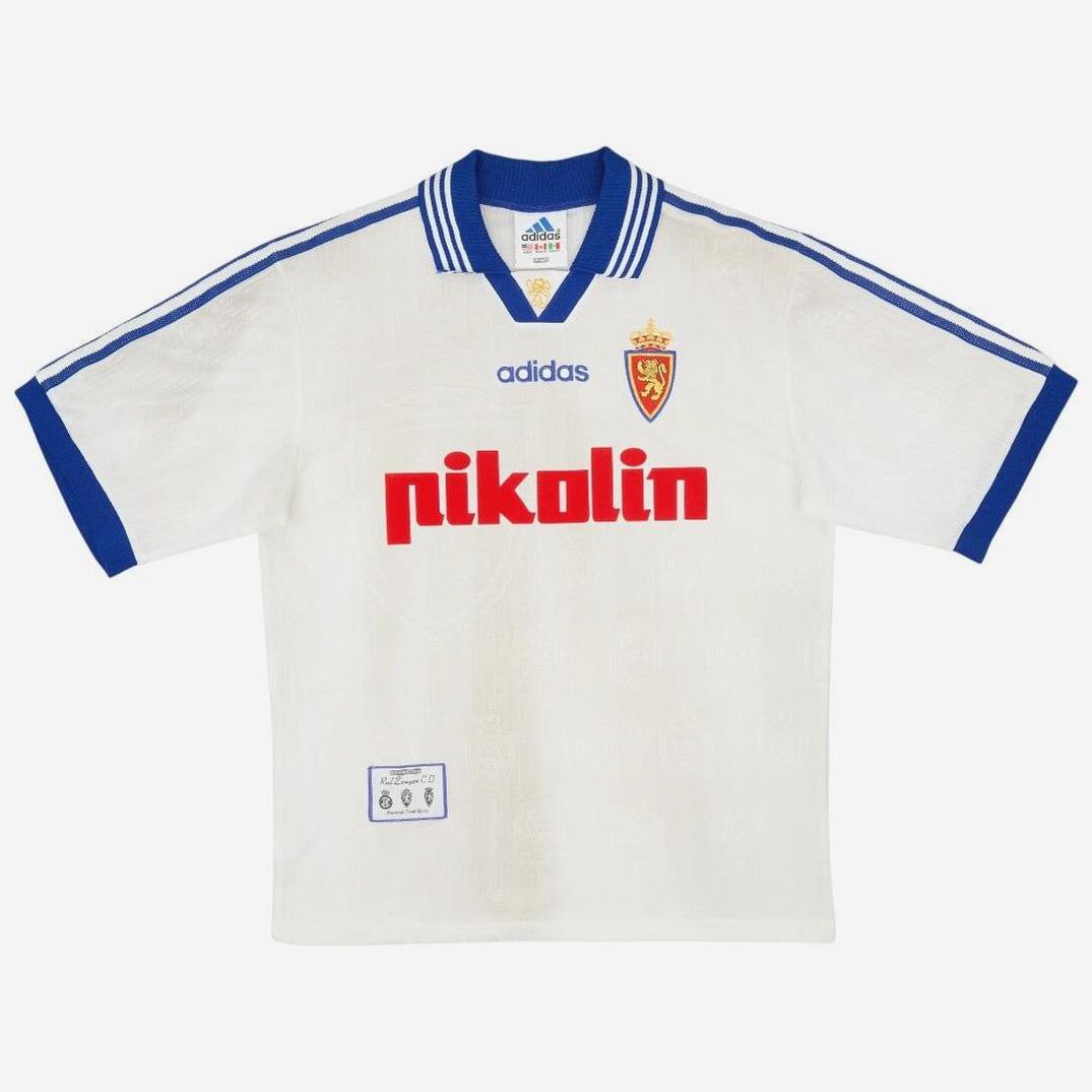 The Real Zaragoza 1997-99 Home Shirt by Retro1999 is a retro-inspired white jersey with blue collar and sleeves, Adidas logo, club crest, and bold red pikolin sponsor—an iconic La Liga classic.