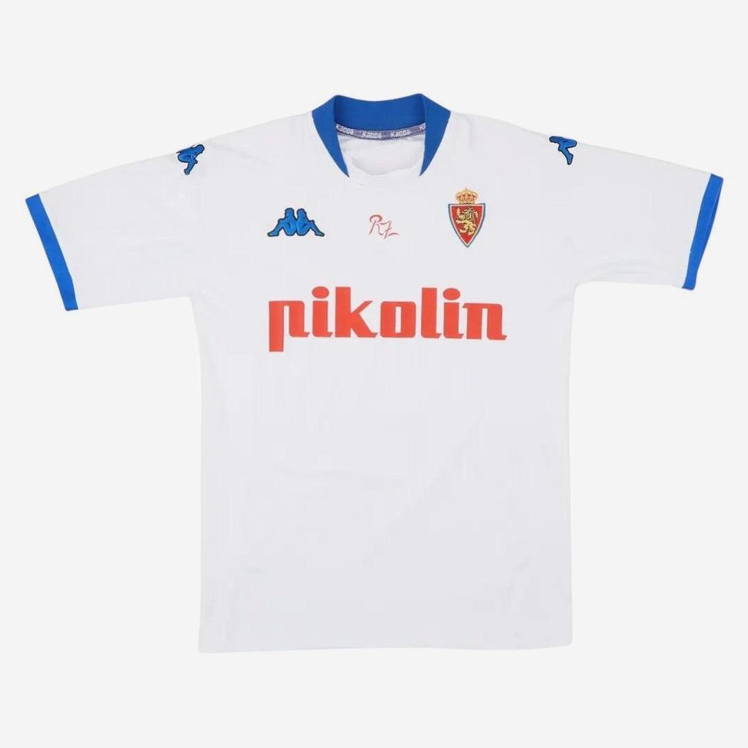 The Retro1999 Real Zaragoza 2001-03 Home Shirt is white with blue collar and sleeves, features the Kappa logo, red club crest, and pikolín sponsor—ideal La Liga memorabilia for retro kit collectors.