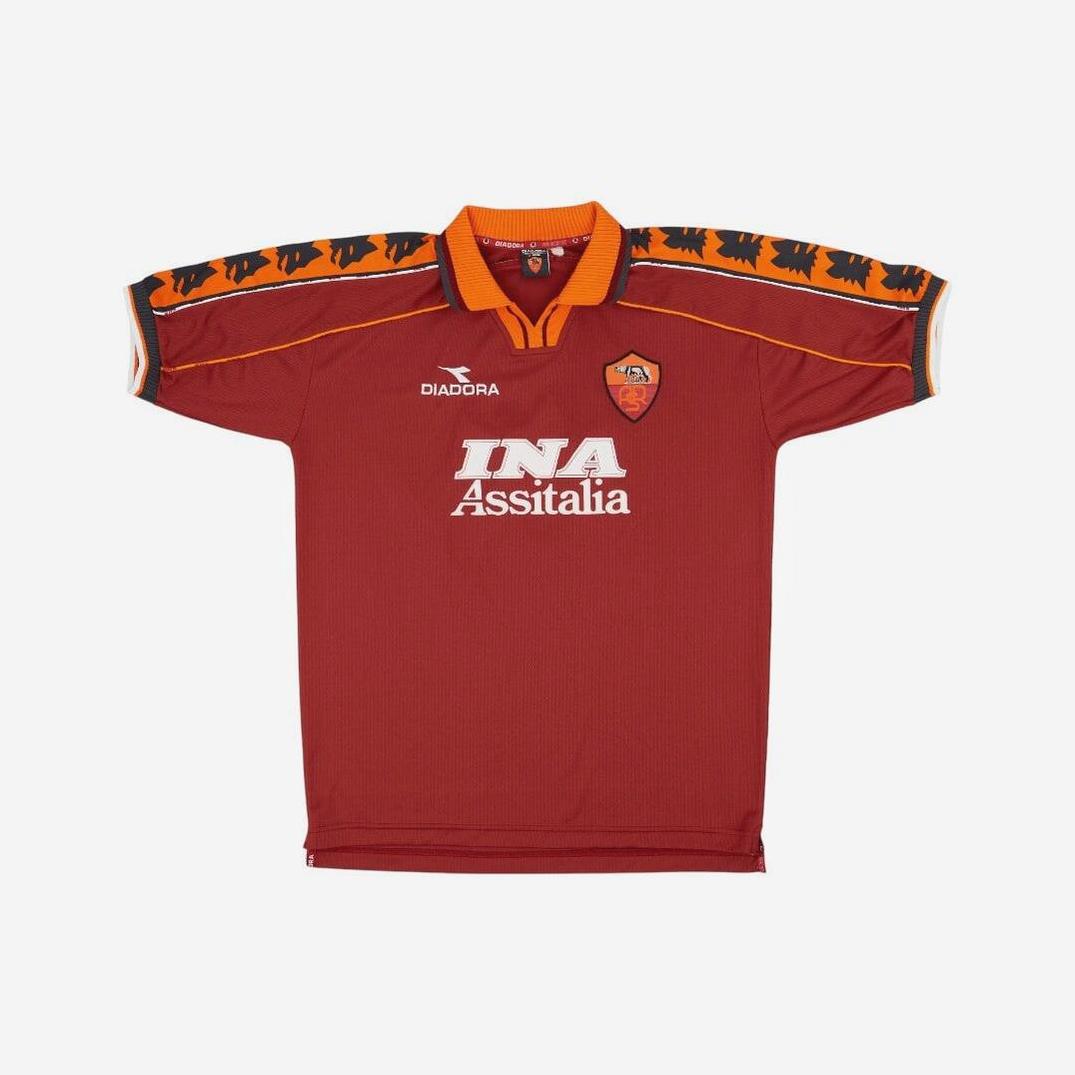 The Retro1999 Roma 1998-99 Home Shirt features vintage red with orange accents, Diadora logo, team crest, INA Assitalia sponsor, and black wolf head sleeve patterns—a classic retro kit for football jersey fans.