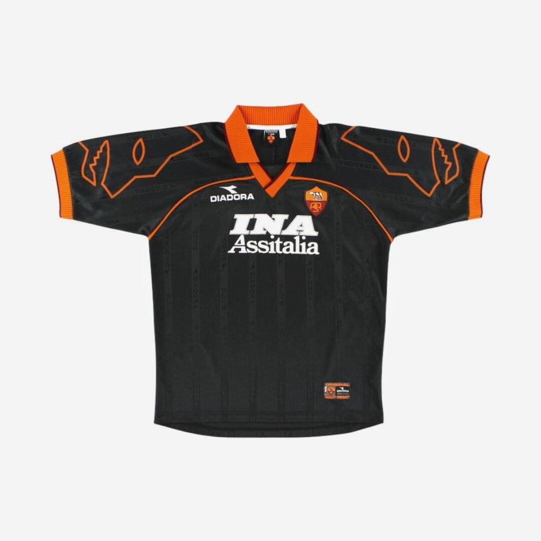 The Roma 1999-00 Away Shirt by Retro1999 features black and orange colors, shoulder accents, club crest, and “INA Assitalia” sponsor—an iconic retro kit from a standout Serie A season.