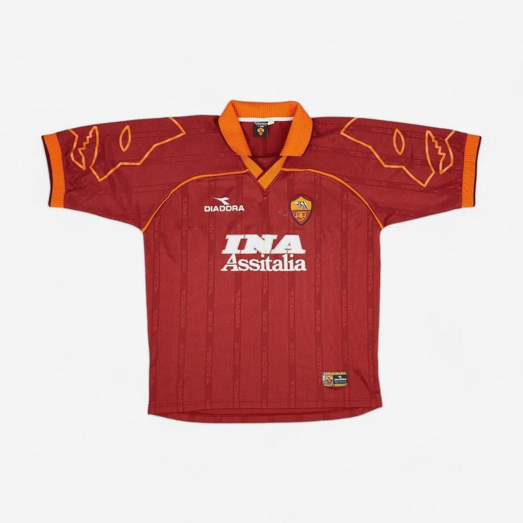 The Retro1999 Roma 1999-00 Home Shirt is a vintage red Serie A kit with orange accents, featuring the Diadora logo, club crest, and INA Assitalia sponsor on the front.