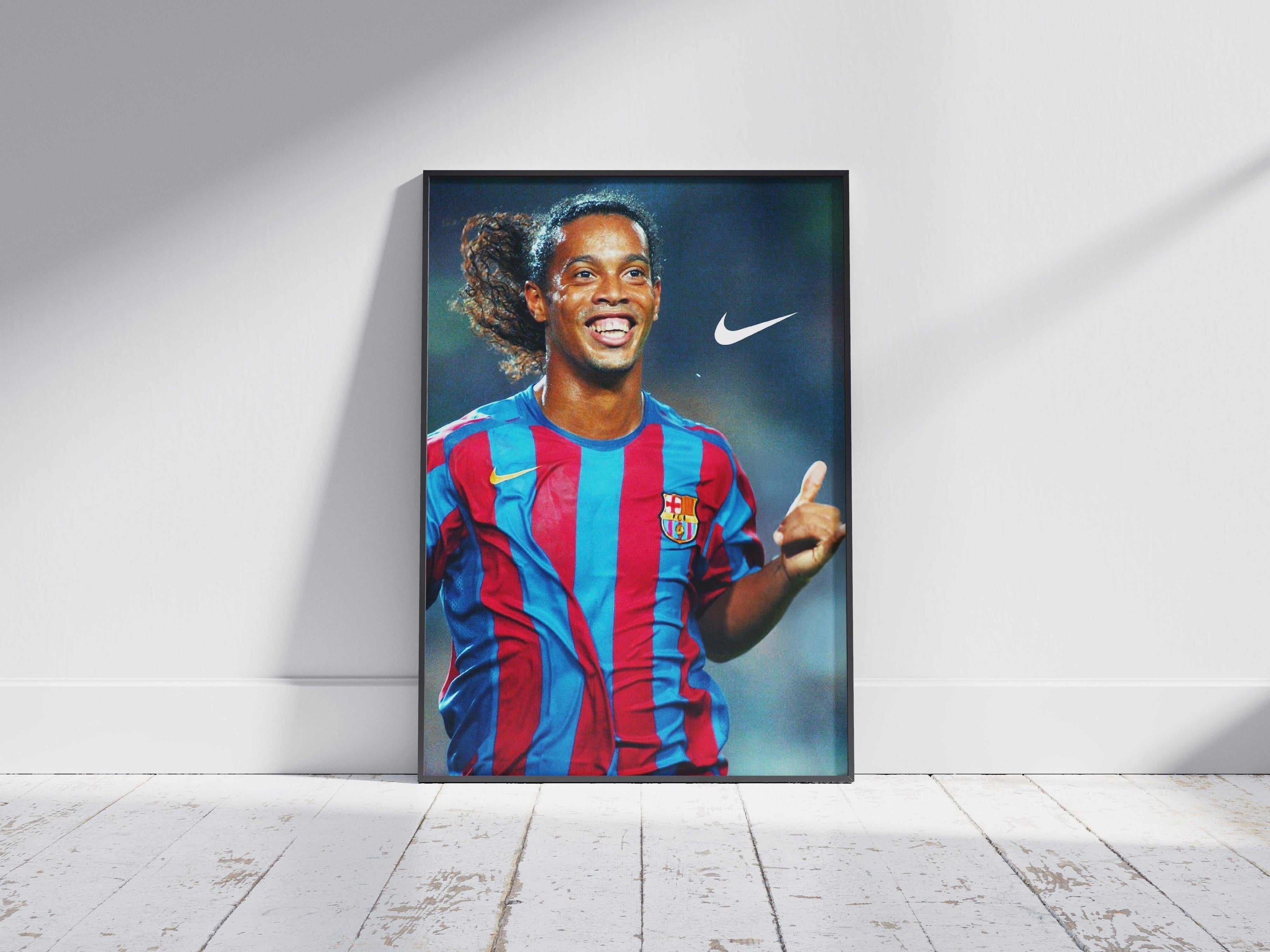 The Ronaldinho Gaucho x Barcelona Poster by Retro1999 features the soccer star in a red and blue jersey with a visible Nike logo, standing on a white wooden floor—perfect football memorabilia for any fan.