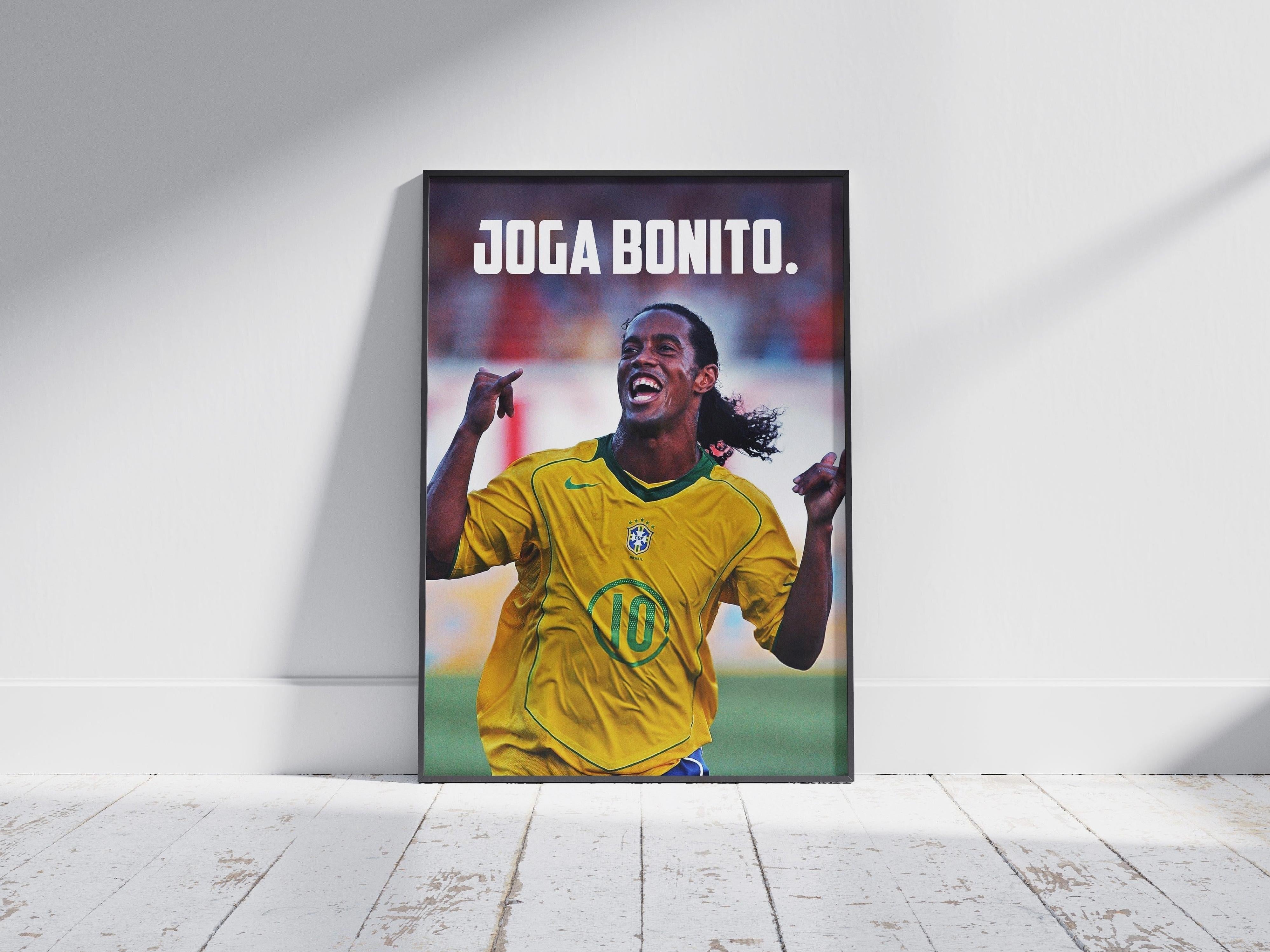 The Retro1999 Ronaldinho Joga Bonito Poster 2 features the soccer legend smiling in a yellow Brazil jersey with JOGA BONITO. above him, framed on a wooden floor—perfect for any football fan’s collection.
