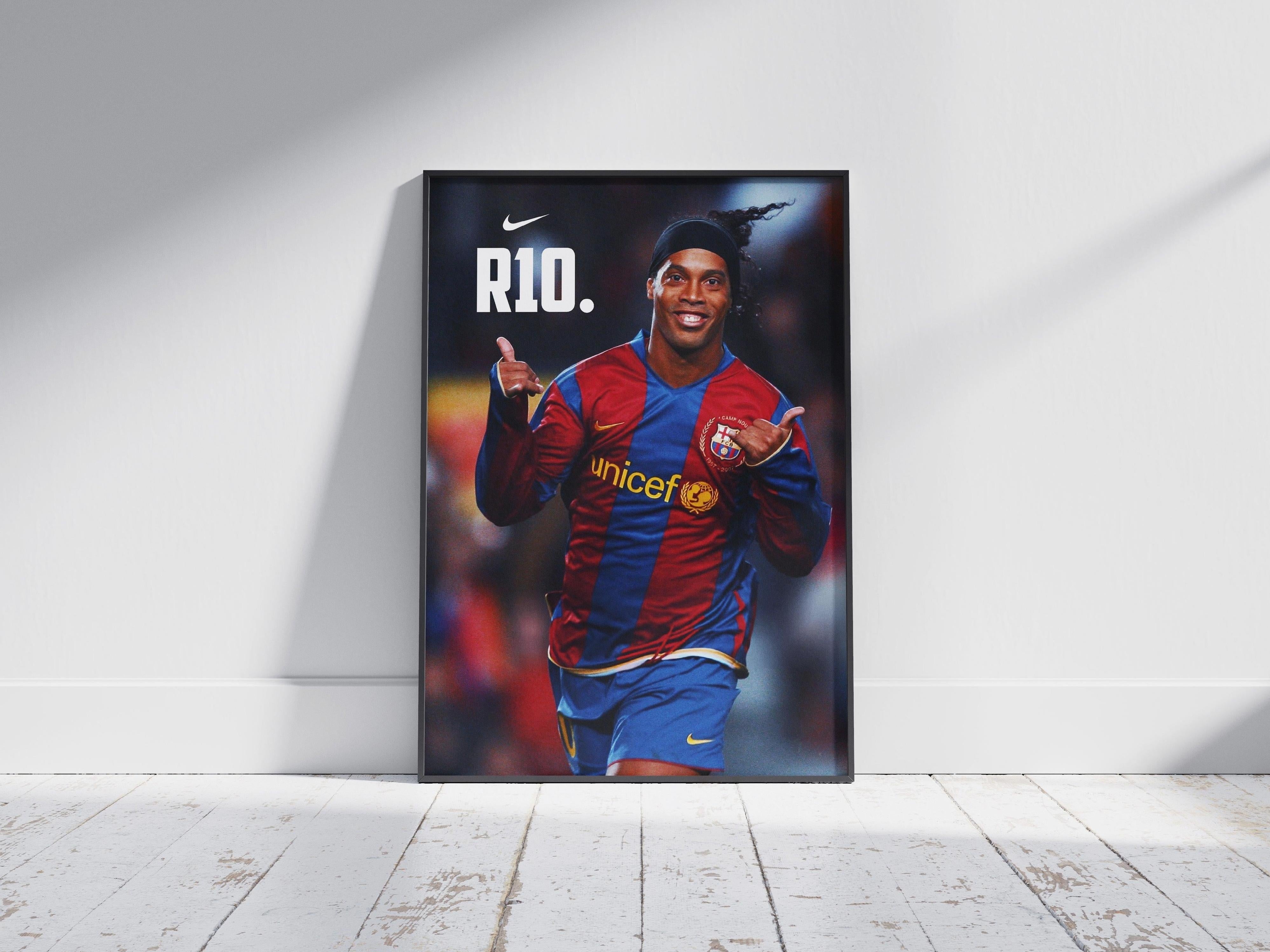 Add iconic sports decor to your space with the Retro1999 Ronaldinho R10 Poster—framed, featuring the soccer legend smiling and pointing in his blue and red jersey. A must-have collectible for any football fan.