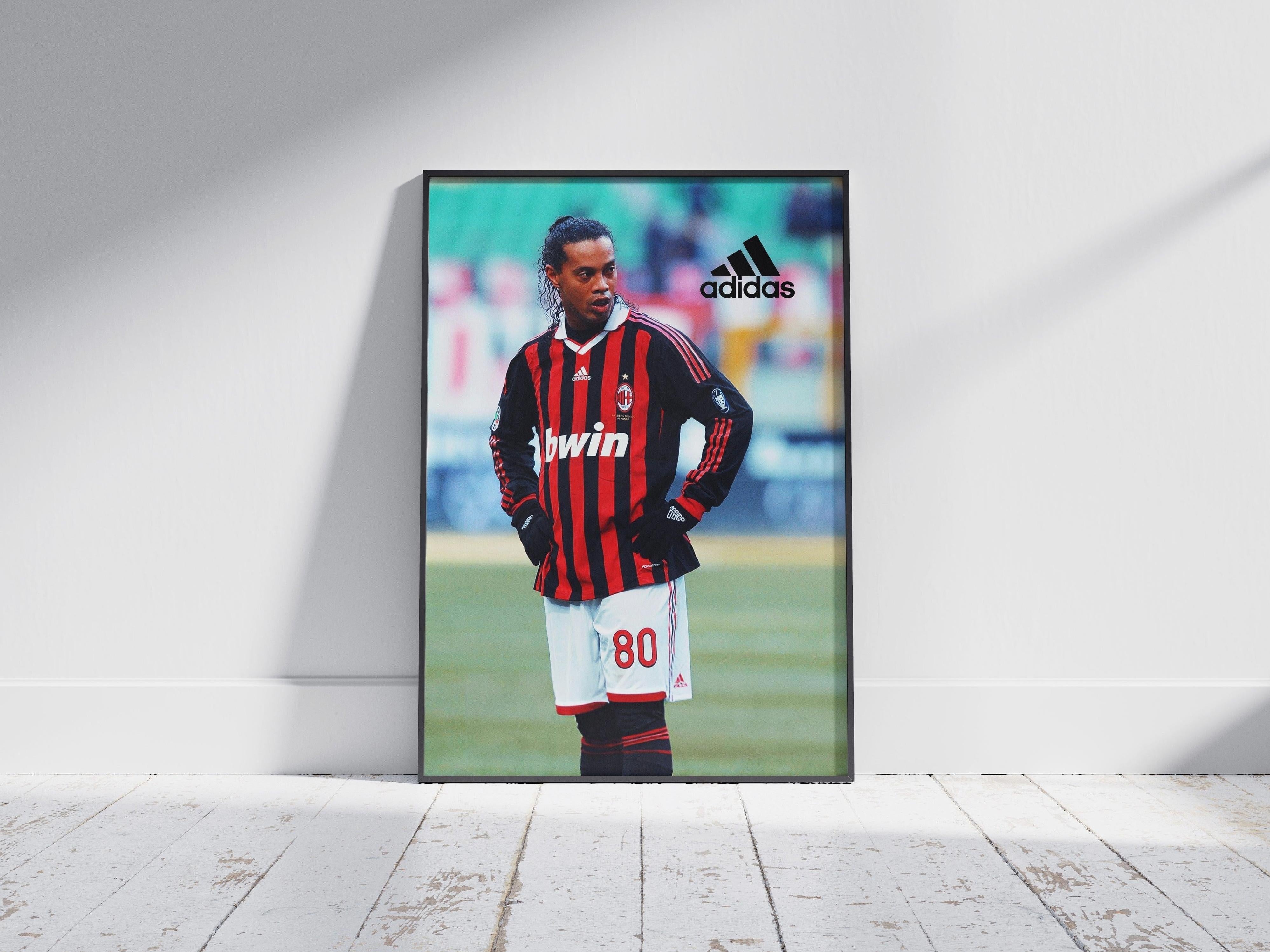 The Retro1999 Ronaldinho x AC Milan Poster shows him in his number 80 kit on the field, with the Adidas logo at the top right. The framed print is displayed against a white wall on a wooden floor.