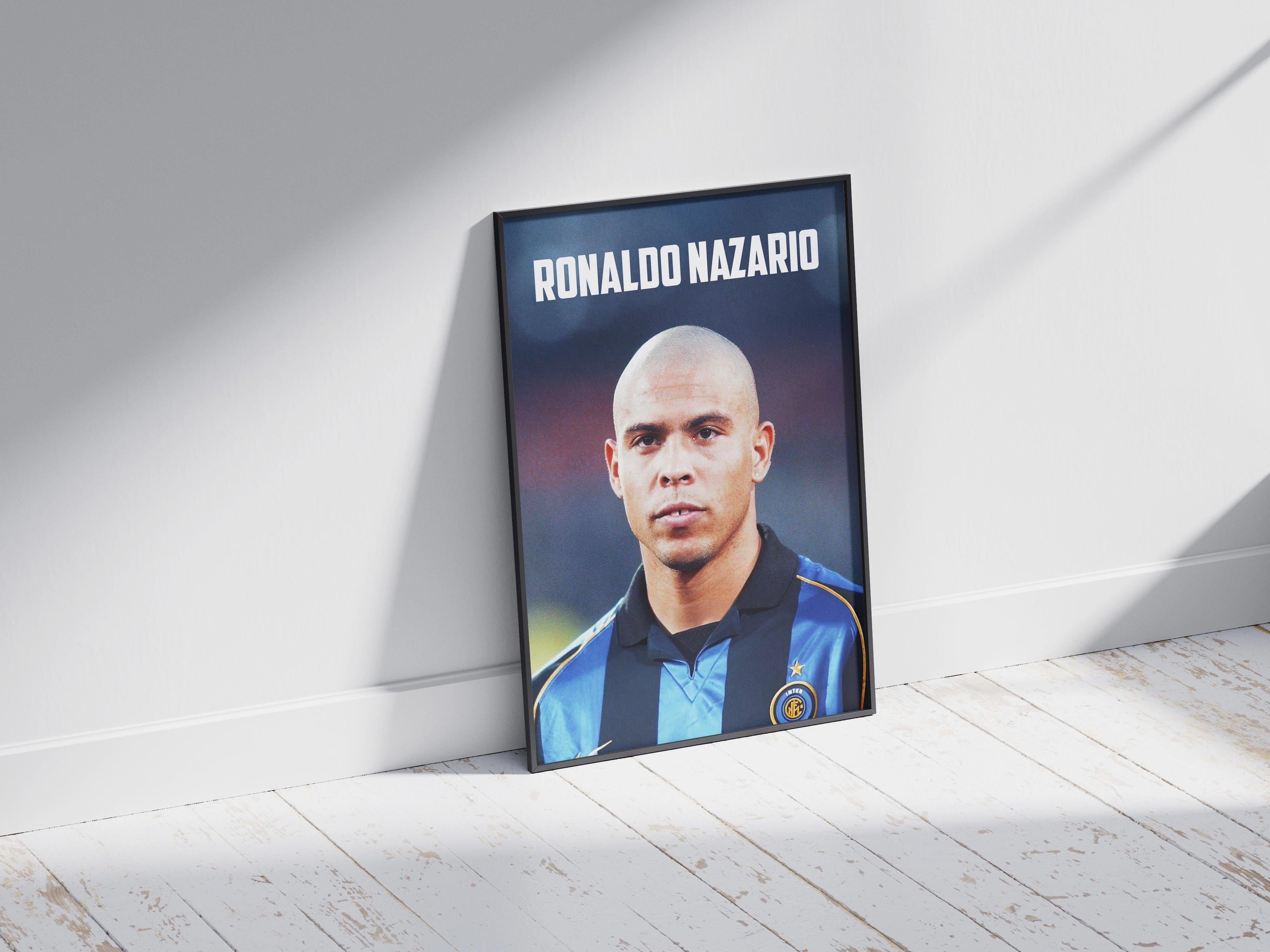 The Retro1999 Ronaldo Nazario Inter Poster features the football legend in an Inter Milan jersey, framed and ideal for fans. Displayed leaning against a white wall on a light wooden floor with sunlight.
