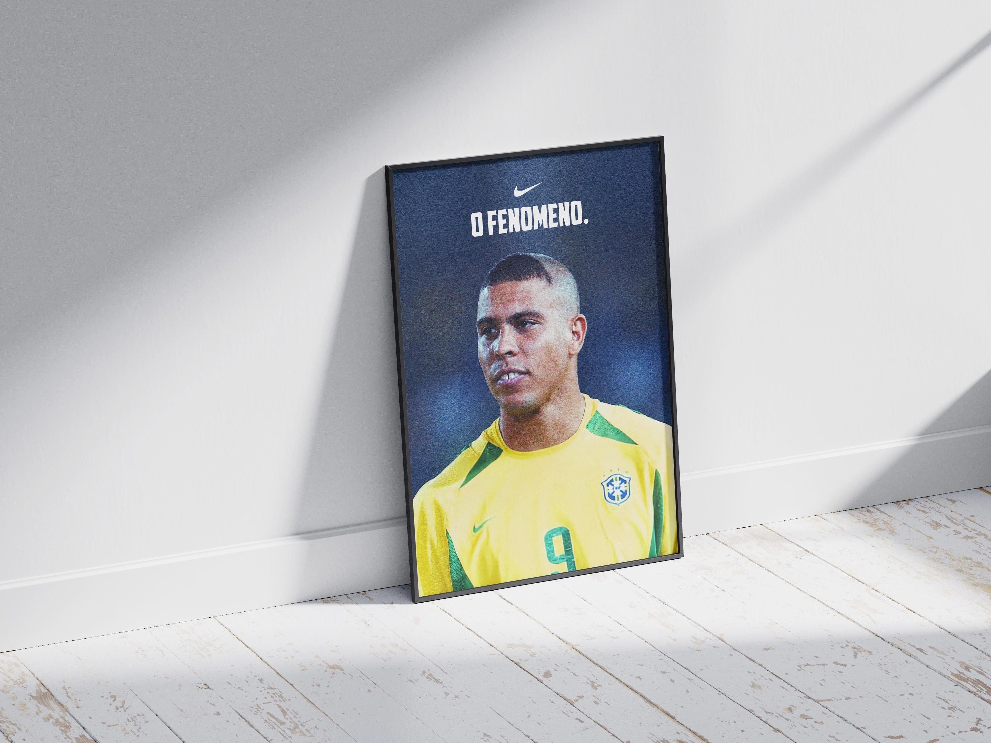 The Retro1999 Ronaldo O Fenômeno Poster features the legendary No. 9 in a yellow jersey, leaning by a white wall with “O Fenomeno” and Nike logo above, celebrating his 2002 FIFA World Cup victory.