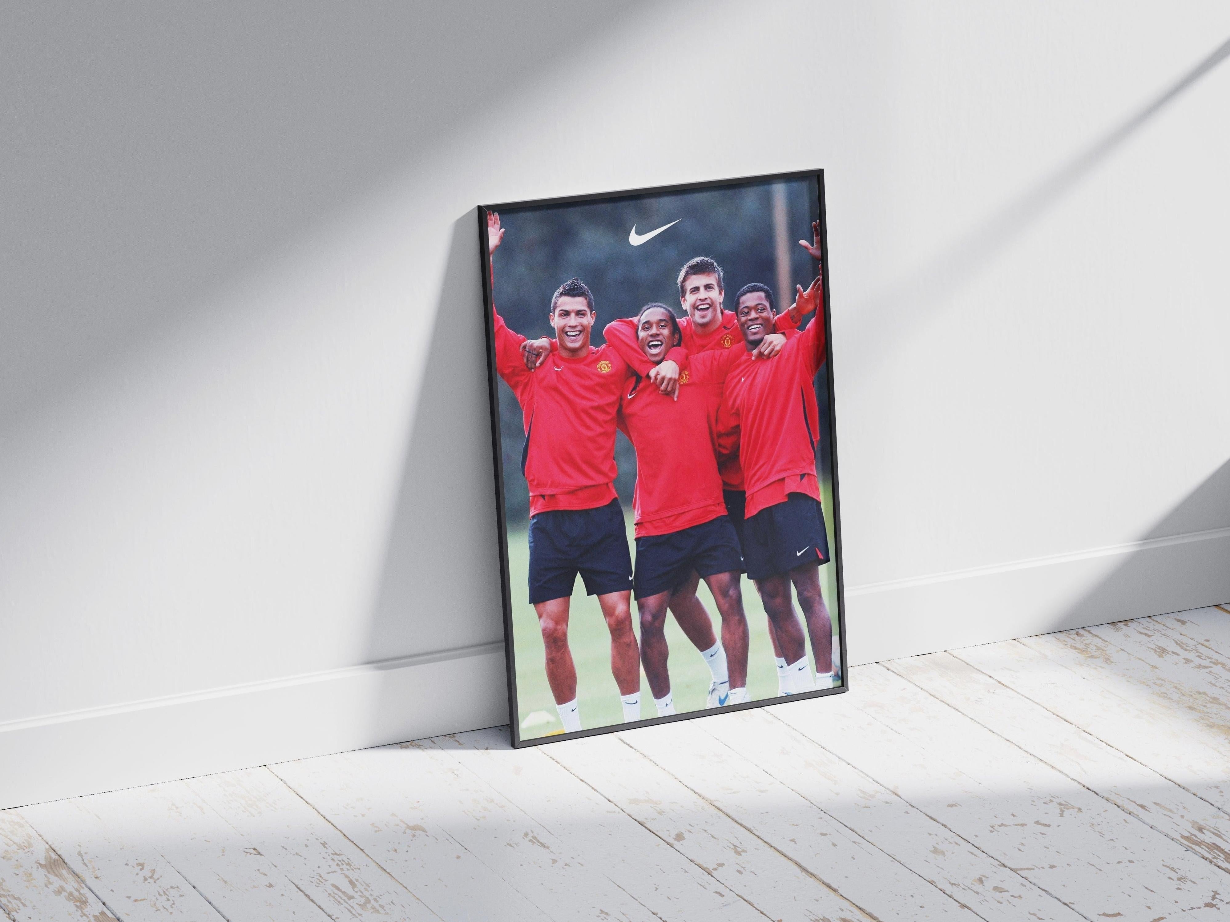 The Retro1999 Ronaldo x Anderson x Pique x Evra Poster features football legends posing in red sportswear with a Nike logo, framed against a white wall and wooden floor—ideal for Manchester United fans.