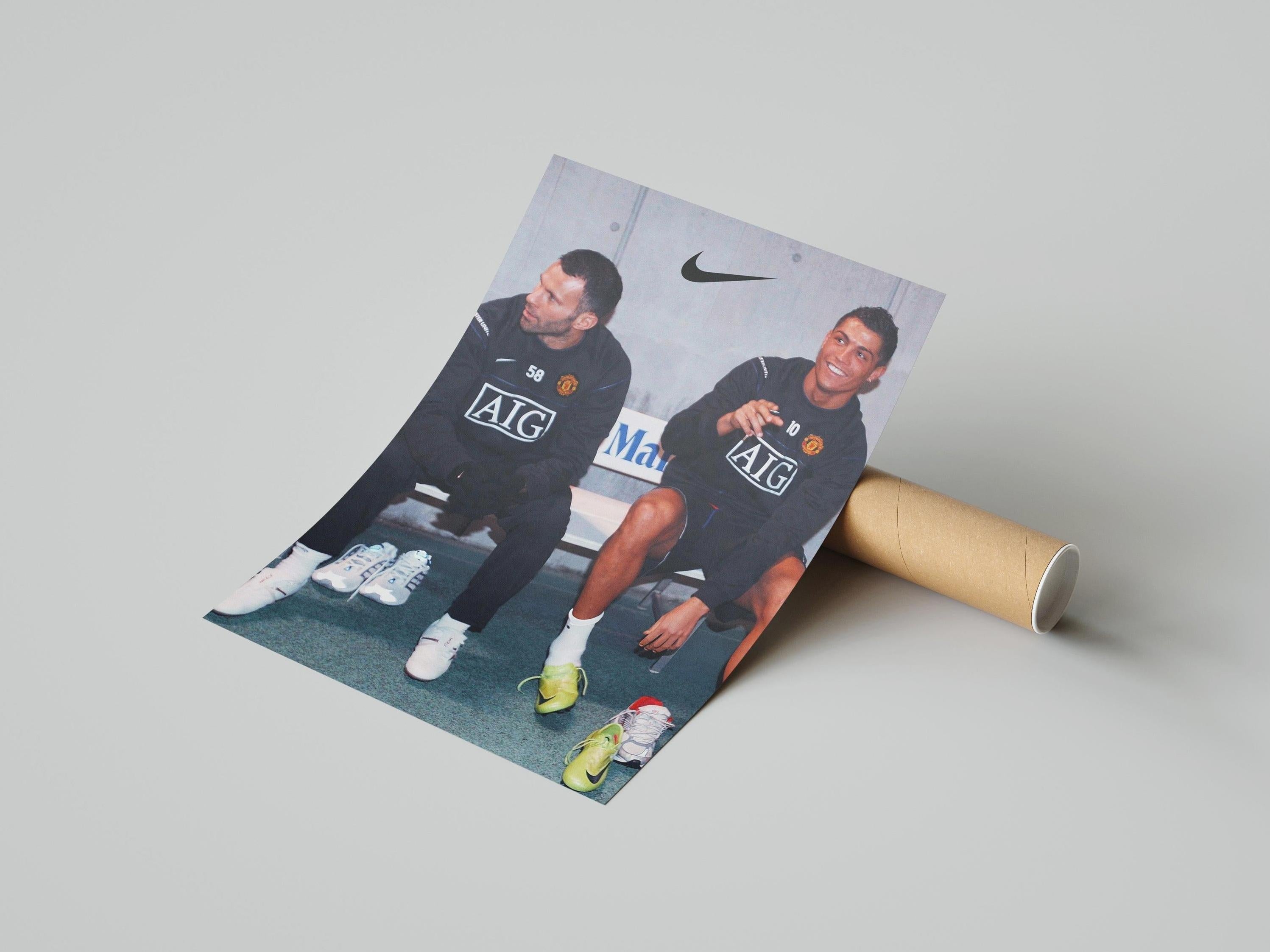 The Retro1999 Ryan Giggs x Cristiano Ronaldo Poster features both legends in Manchester United tracksuits, relaxed and shoeless on a bench, with the Nike logo displayed above them.