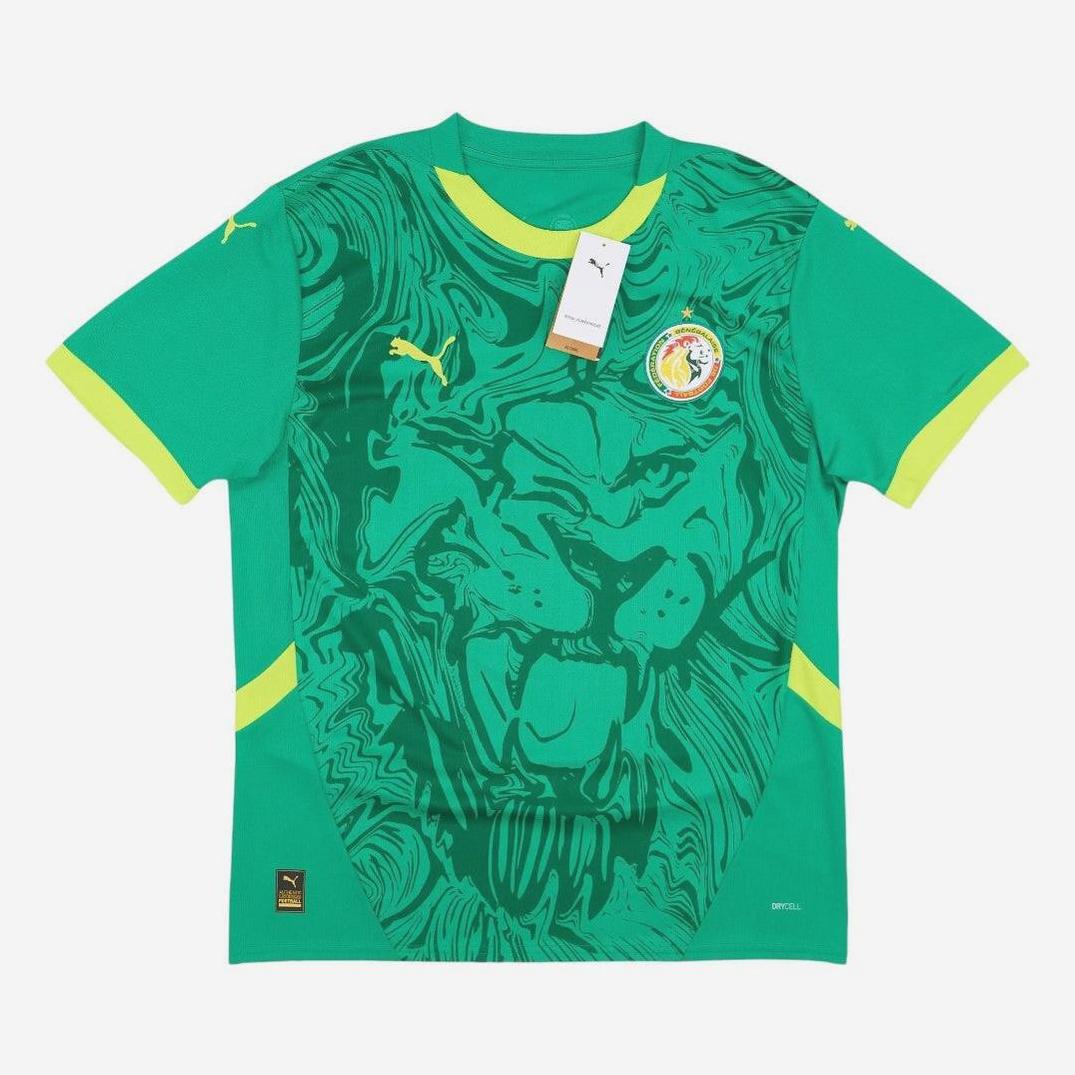 The Retro1999 Senegal 2024-25 Away Shirt is green with yellow accents, a bold lion face graphic, national team crest, Puma logos, and a collar tag—blending retro kit style with modern details.