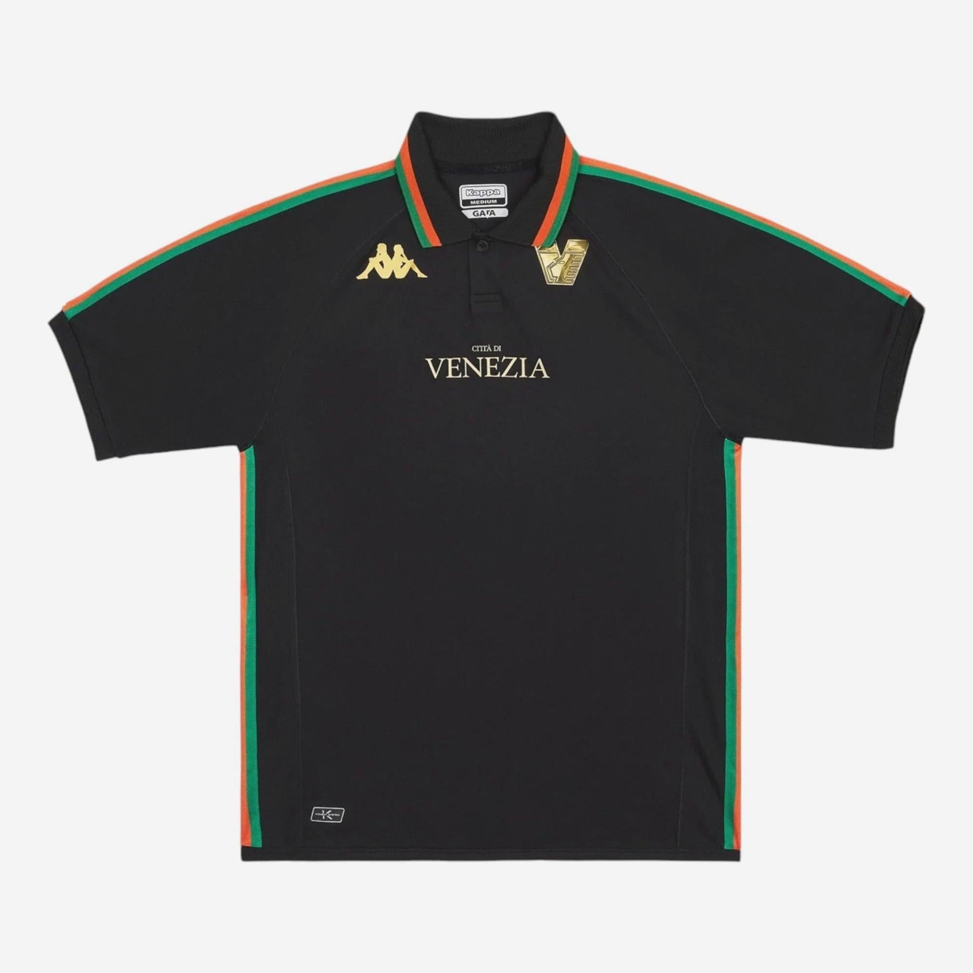 The Retro1999 Venezia 2022-23 Home Shirt is a black polo inspired by Venezia FC, featuring gold Kappa logos, gold Venezia text on the chest, and green-orange stripes on the shoulders and sides.