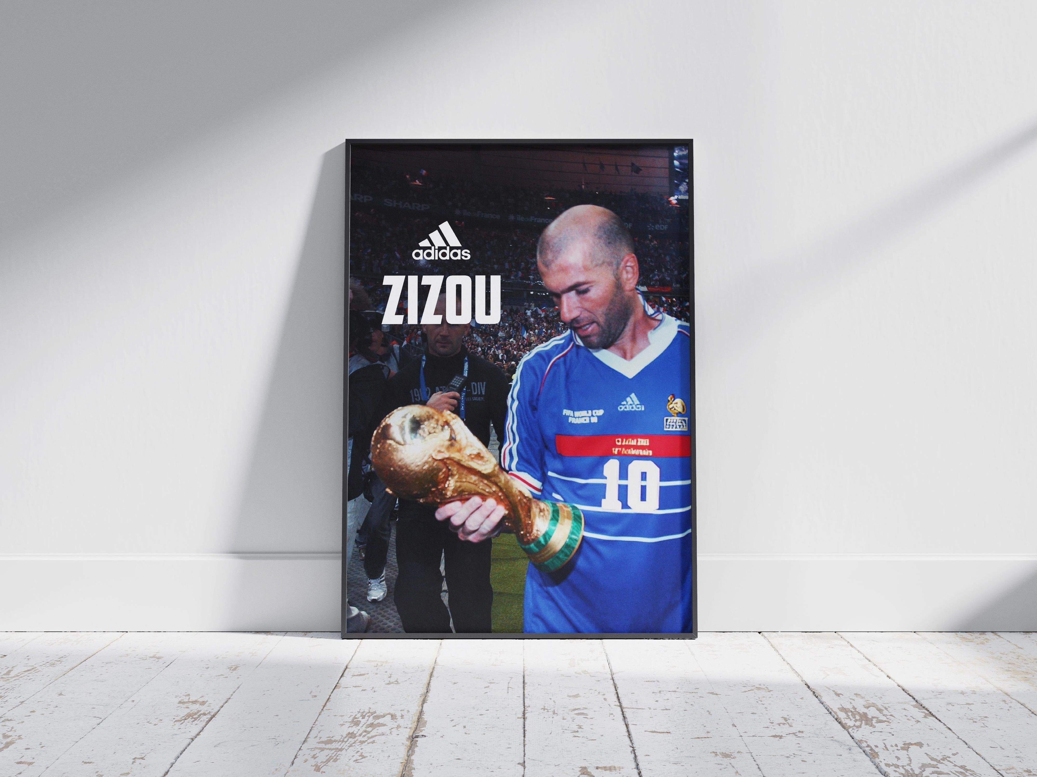 The Zinedine Zidane Zizou Poster by Retro1999 shows the soccer legend in a blue jersey holding the FIFA World Cup trophy, with adidas ZIZOU and his number 10 above—celebrating iconic football history.